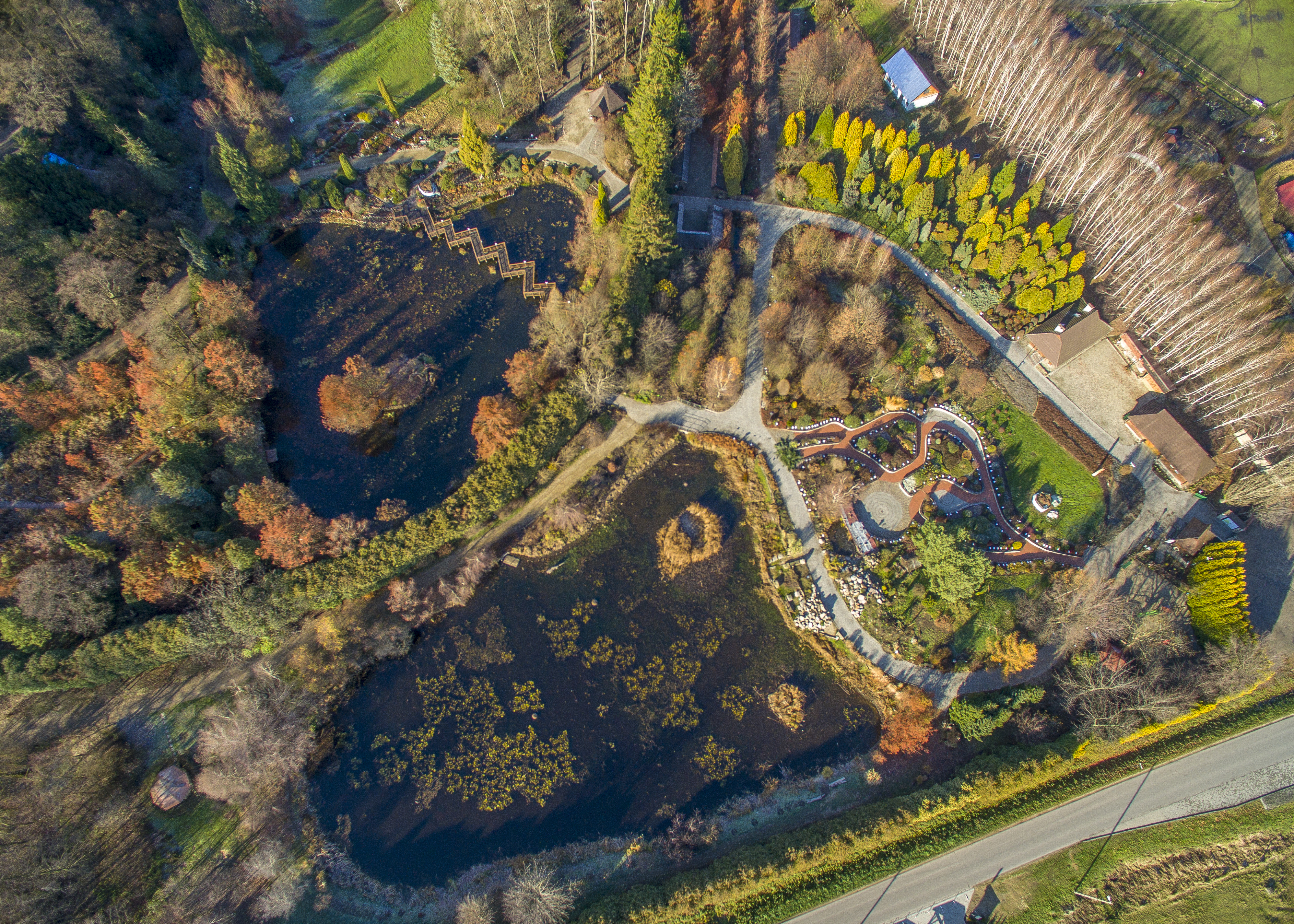 Widok z lotu ptaka na ogród sensualny, po lewej widać alejki i kopiec ziemi a po prawej dwa domy Arboretum.