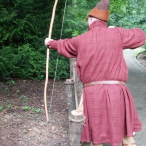 Zdjęcie łucznika w stroju z epoki szykującego się do strzału